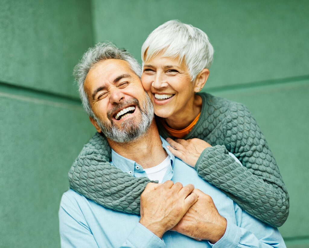 Woman in green sweater hugging man in blue shirt by green wall